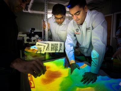 A group of faculty members surrounding a pile of sand. 