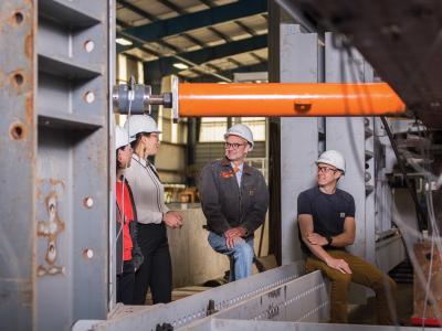A group of four faculty members at a construction site, talking among themselves. 