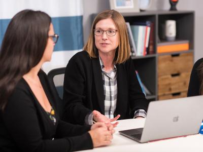 Three faculty members discuss among themselves at a table. 