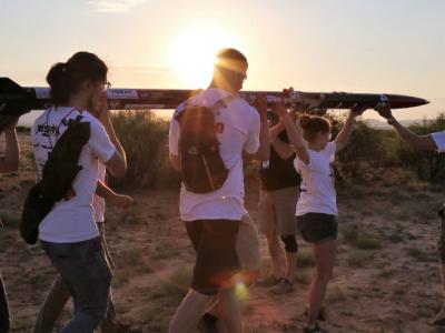 Group of students carrying their project on the beach.