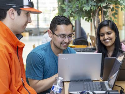 A group of people watching a laptop while smiling. 