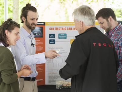 A group of people observing the presentation pamphlet of a student. 