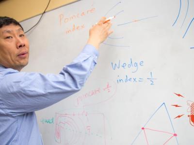 Professor Eugene Zhang drawing on whiteboard.