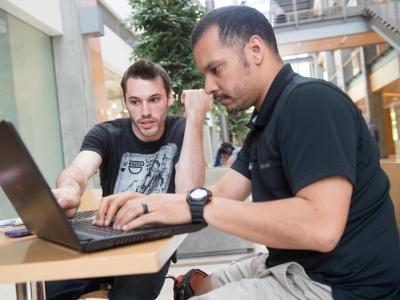 Two students working together on a laptop.