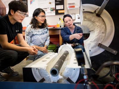 Two engineer students being taught by professor.