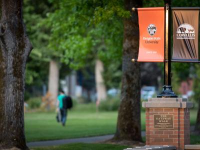 A student walking near display banners outdoor on campus.