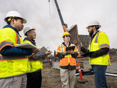 Four construction engineering researchers at a site in hard hats.