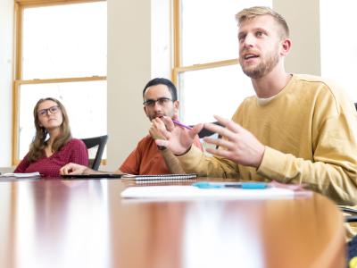 Three students sit at a table in Kearney Hall.