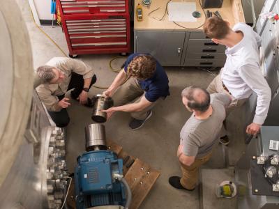 Faculty member Brian Woods with three nuclear engineering researchers in the lab.