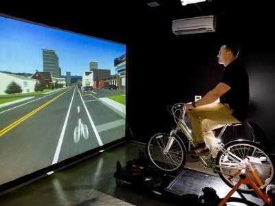 Person riding a bike in front of a screen.