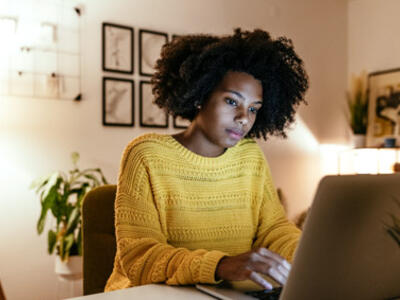 A girl in yellow sweater looking at the laptop, seems to be in a online meeting