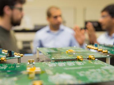 A circuit board in front of a group of people. 